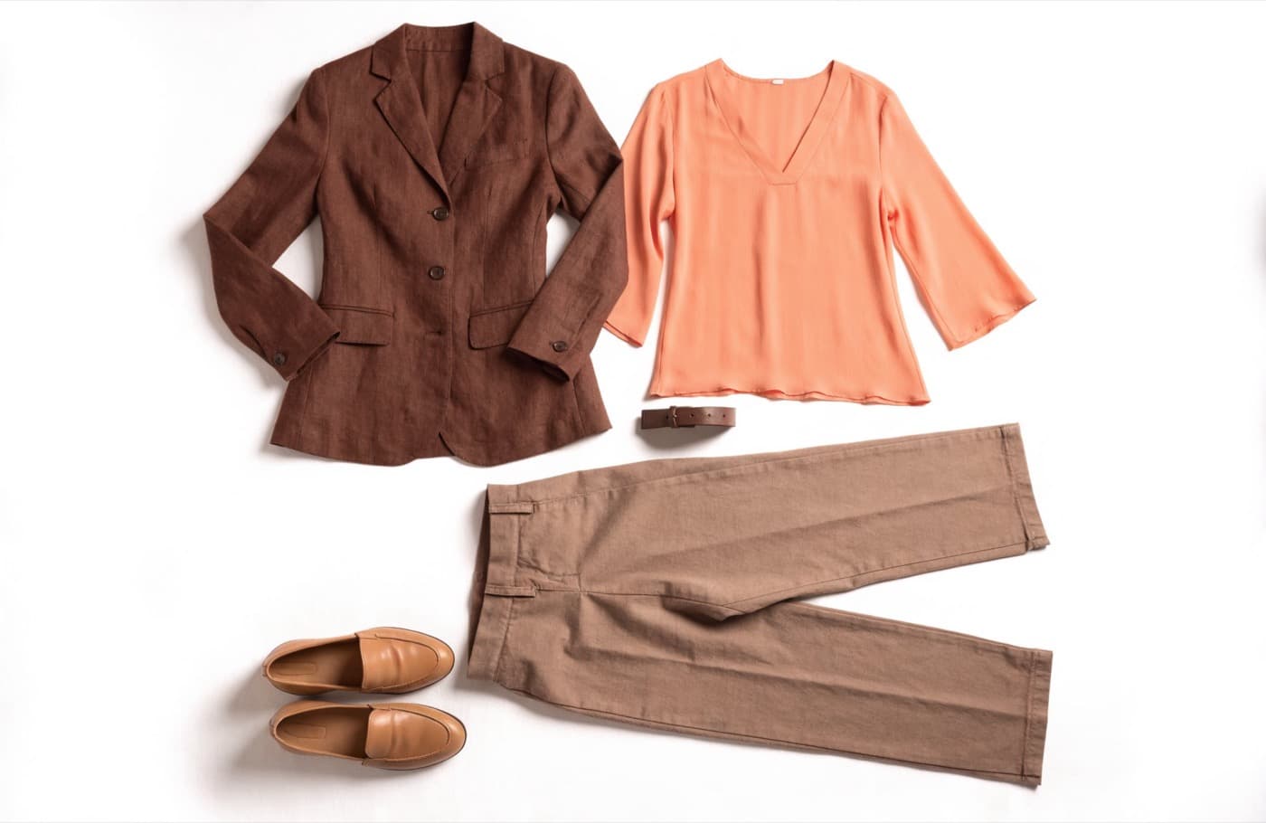 Conjunto completo dispuesto sobre fondo claro: blazer, blusa, pantalón, cinturón y zapatos, en tonos chocolate, durazno y camel.